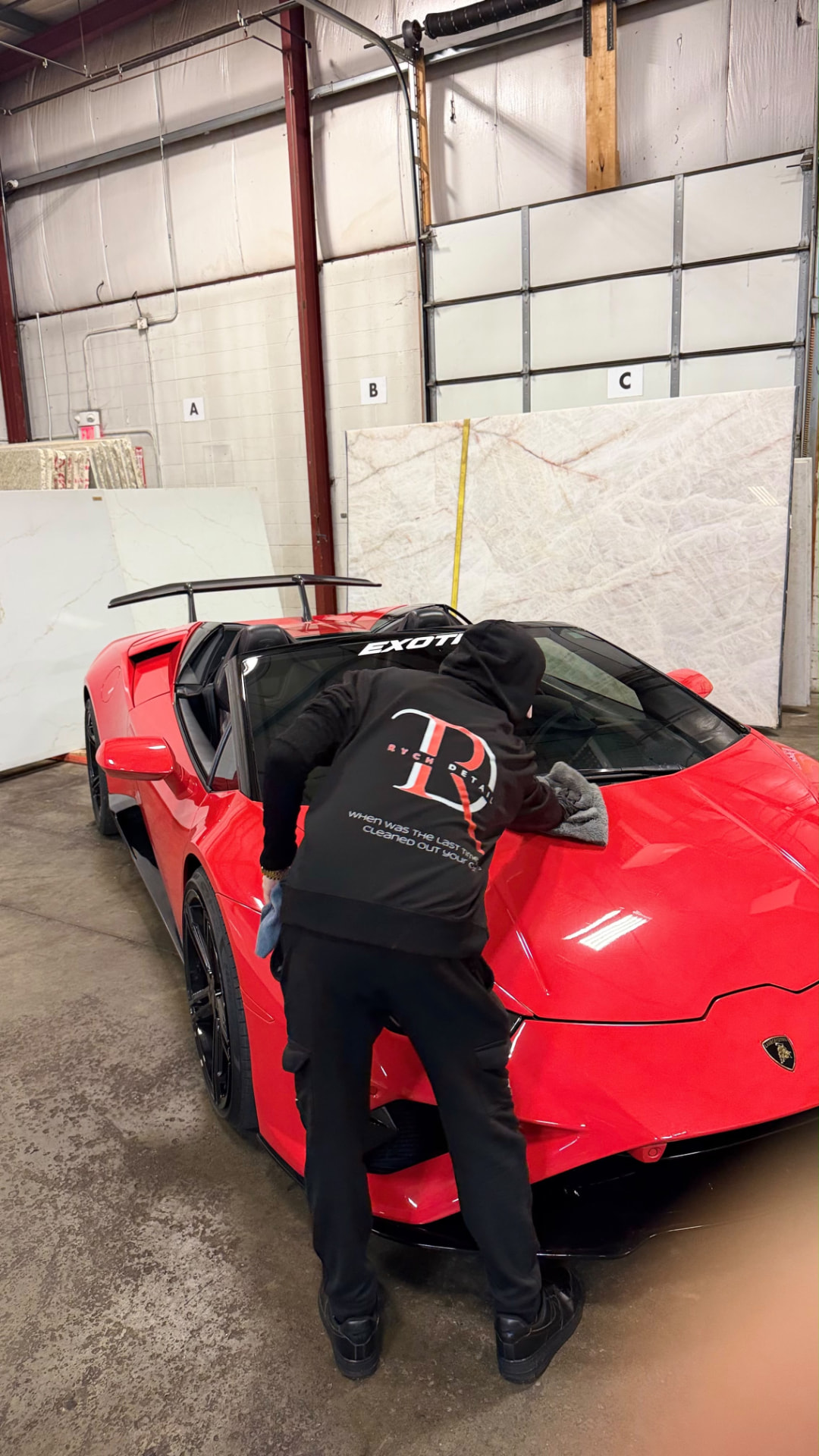Rych Detail hoodie wiping down a red Lamborghini
